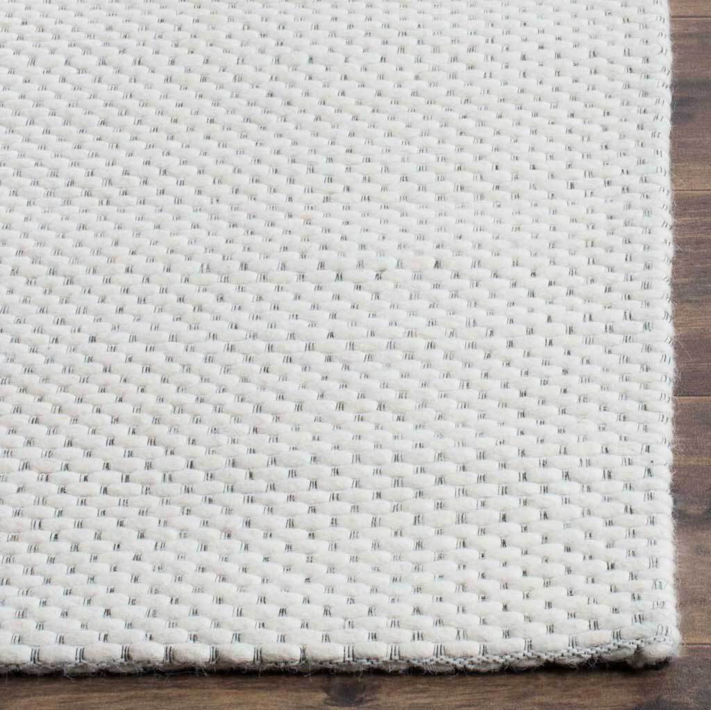 Plump ivory loops and neatly finished edges lend inviting texture to the rug.