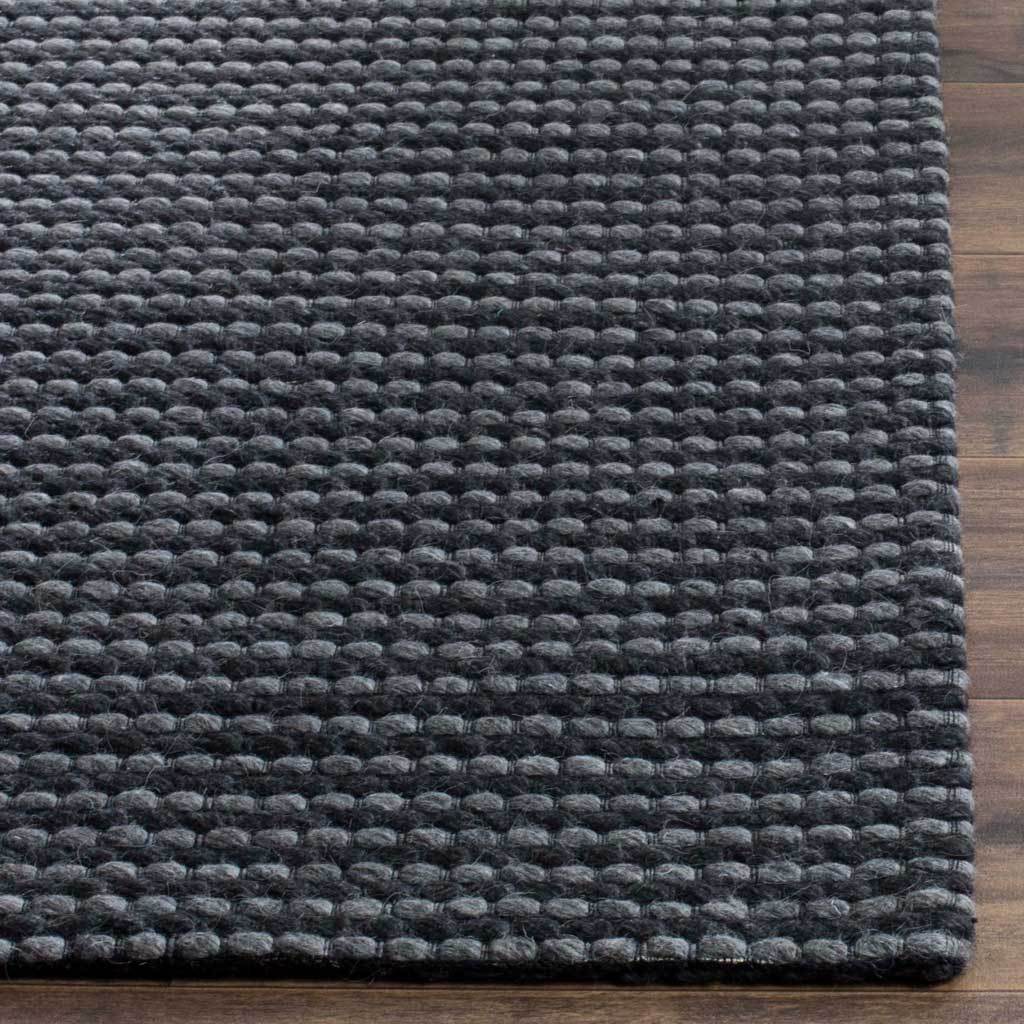 Rounded gray loops against dark threads add depth to the rug's finished corner.