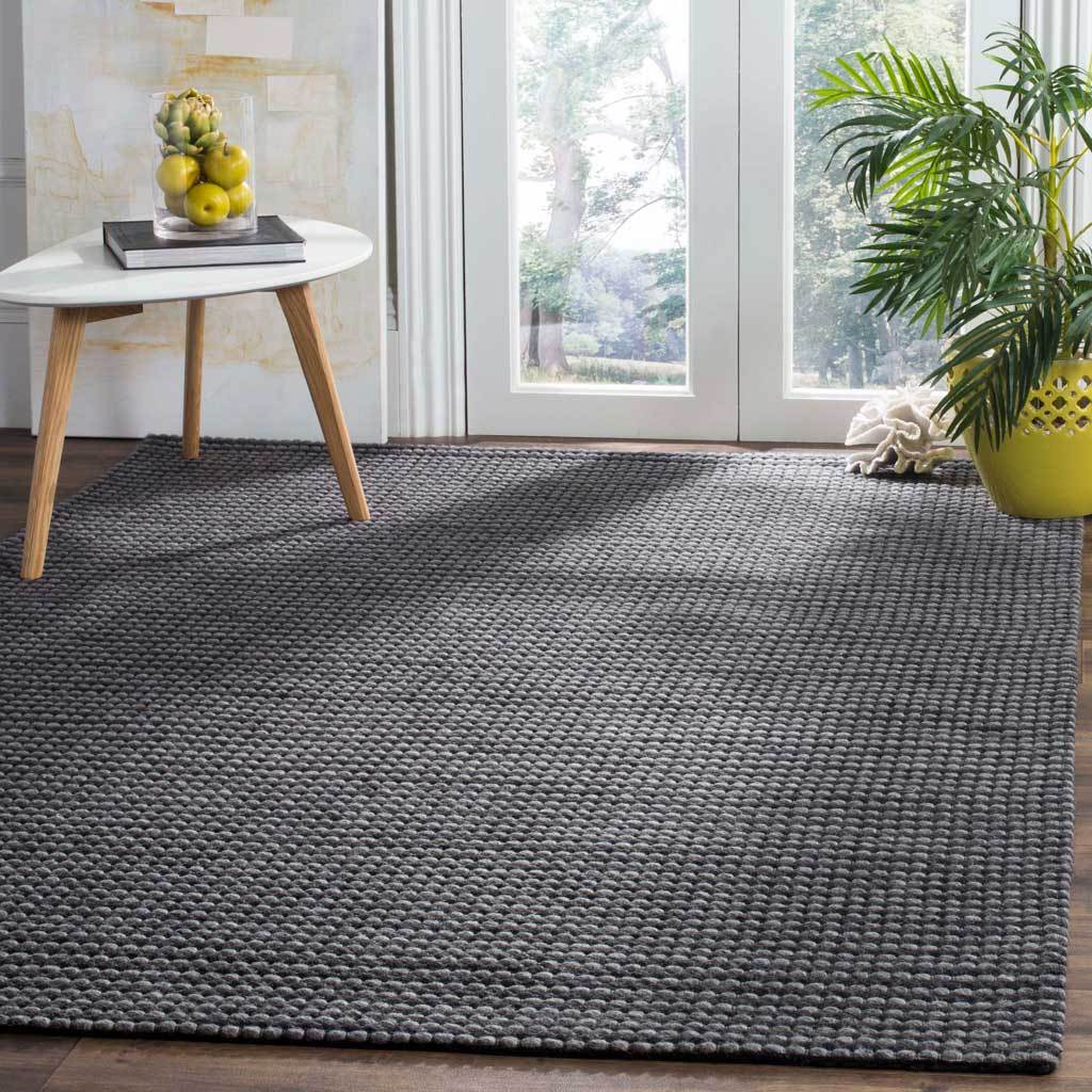 A charcoal-toned rug grounds a bright interior with a bold, tactile weave.