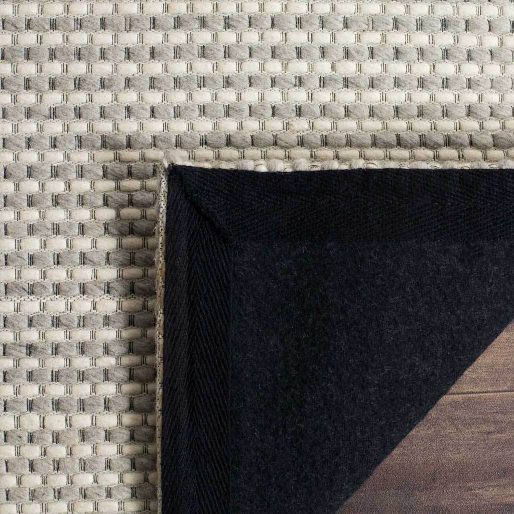 A turned-back corner reveals dark felt backing beneath the silver-and-ivory weave.