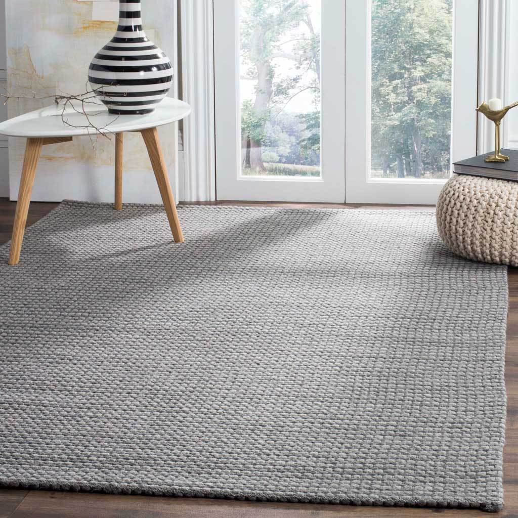 A dark gray woven rug anchors a light-filled space with quiet contrast.