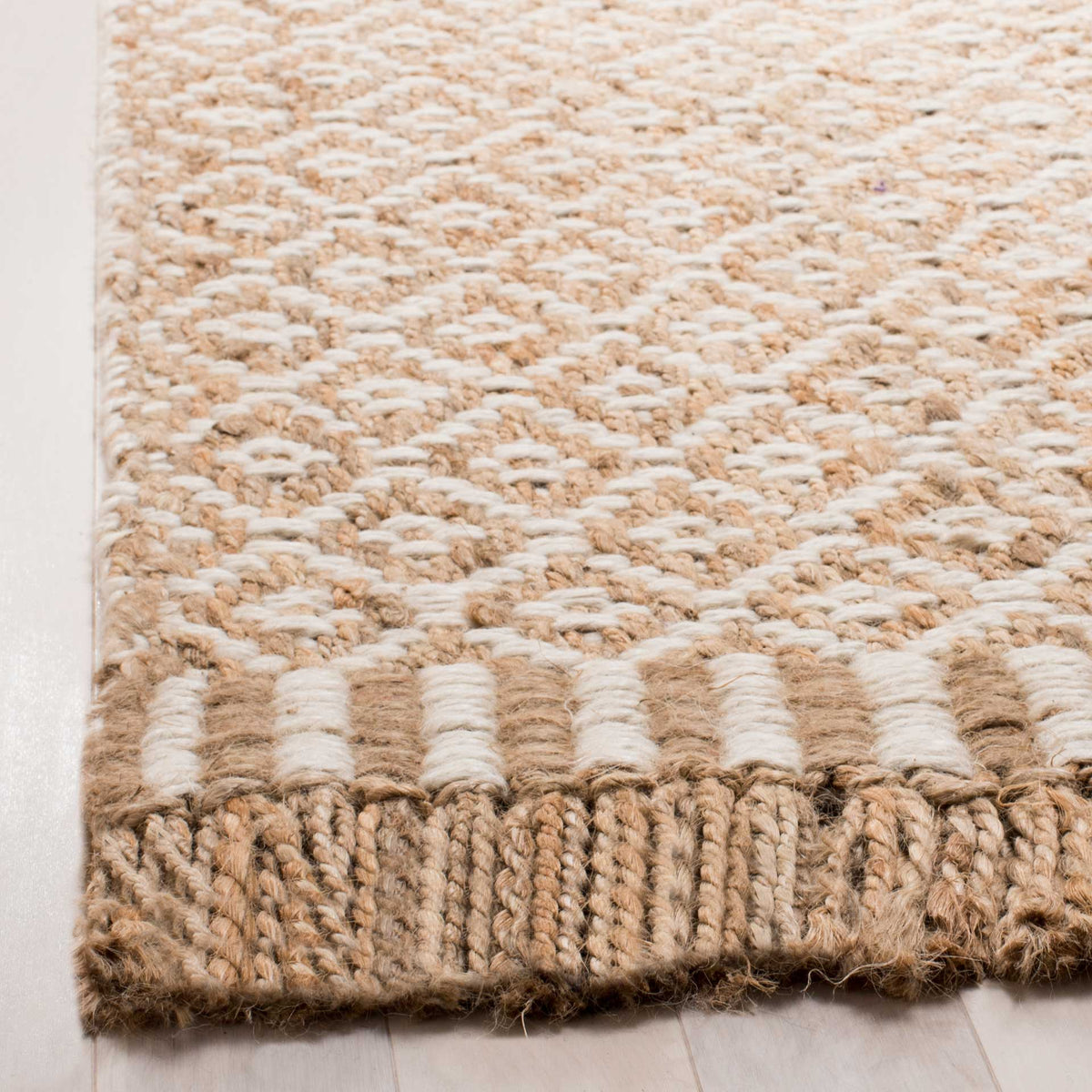 Ivory motifs meet a striped woven band and thick natural fringe at the rug's edge.
