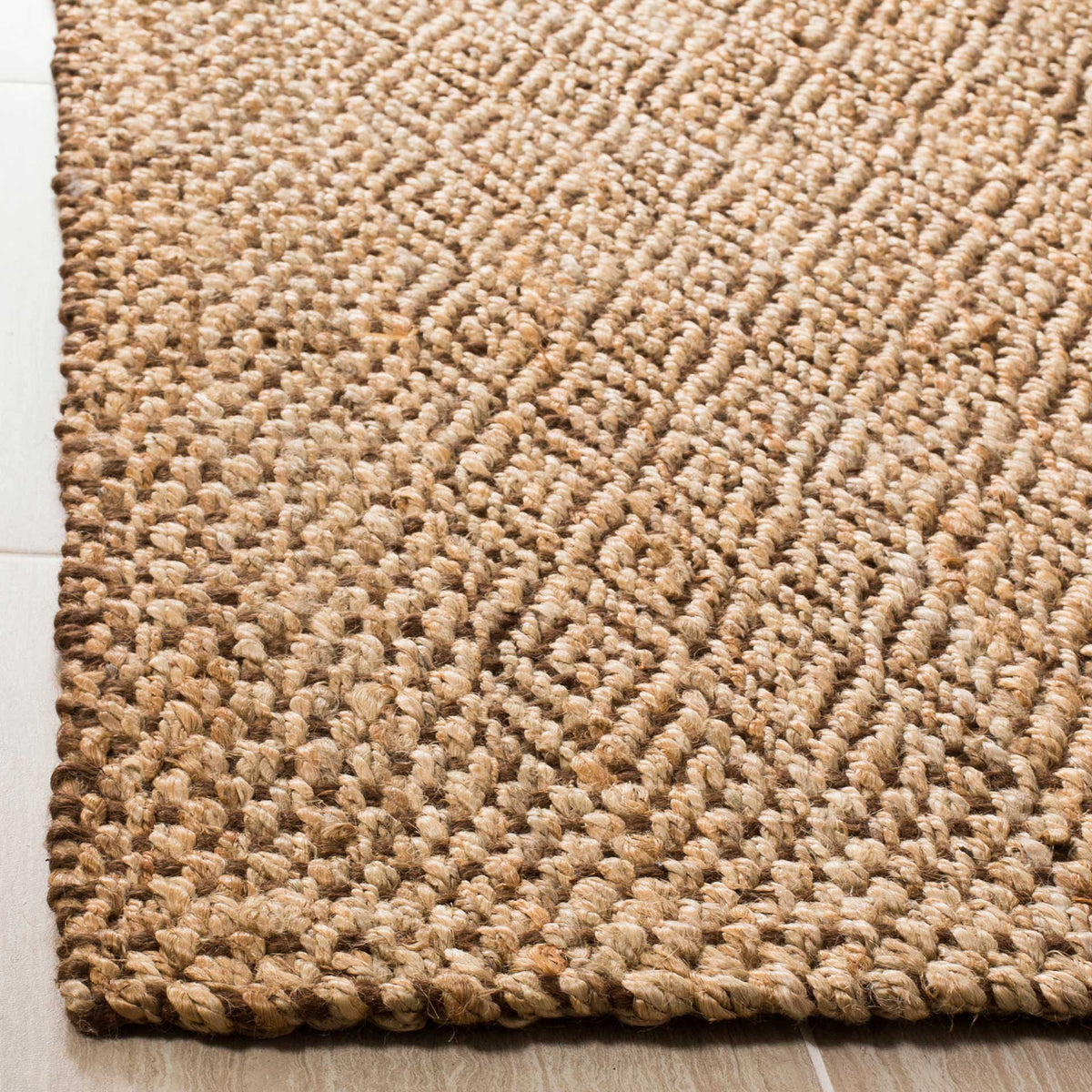 Raised jute diamonds transition to a chunky woven border at the rug's corner.