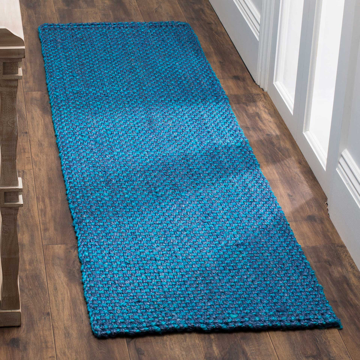 Vivid blue jute runner adds bold color and woven texture to a wood-floored hallway.