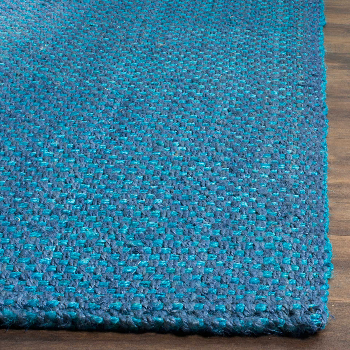 Bright and deep blue jute fibers interlace at a neatly finished rug corner.