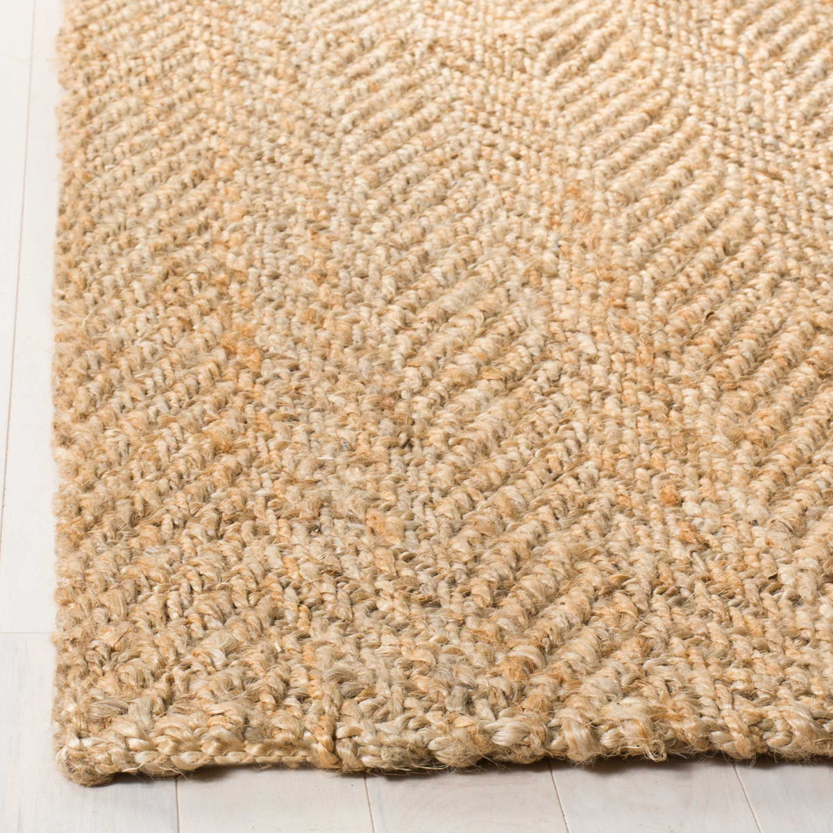 Thick jute strands trace raised chevrons across a neatly finished rug corner.