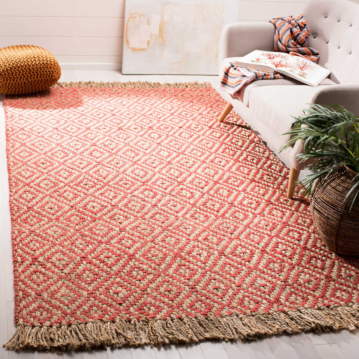 Vibrant coral diamonds enliven a natural jute rug beside a pale upholstered sofa.