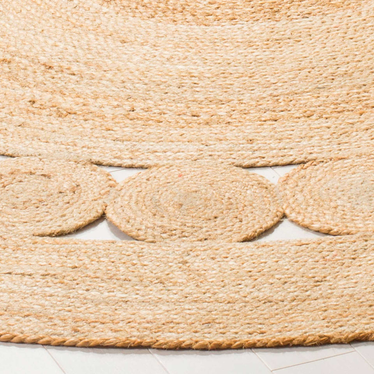 Woven jute medallions and open triangular gaps give the rug's perimeter a textured finish.