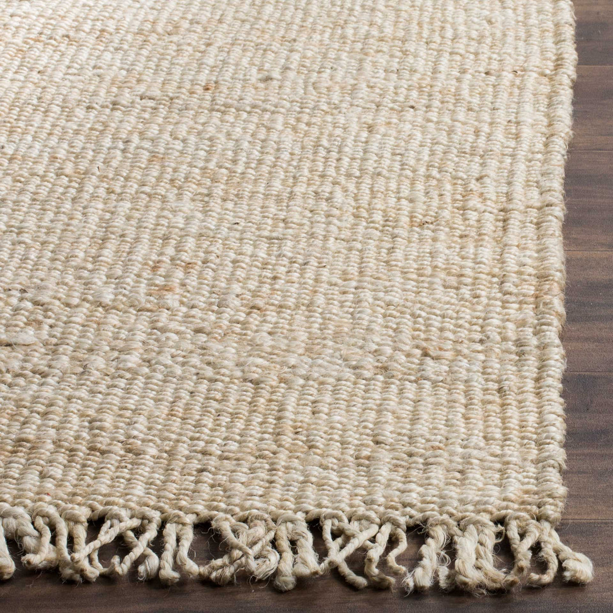 Chunky ivory jute stitches finish the corner beside loosely knotted fringe.