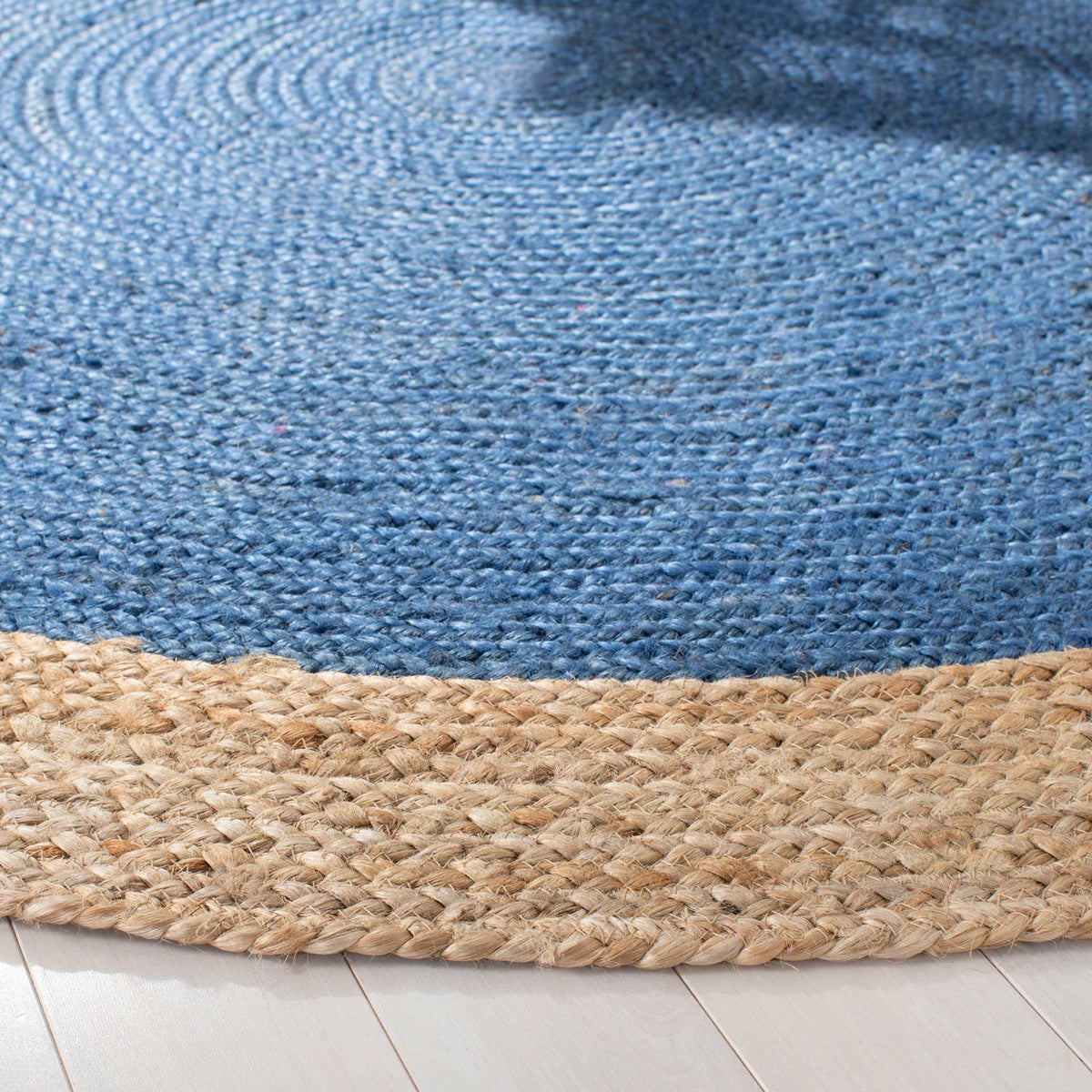 Raised blue jute spirals meet a sturdy natural border along the rug's softly curved edge.