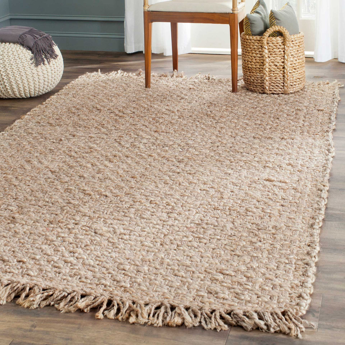 A textured tan jute rug with knotted fringe makes a relaxed foundation beneath a chair.