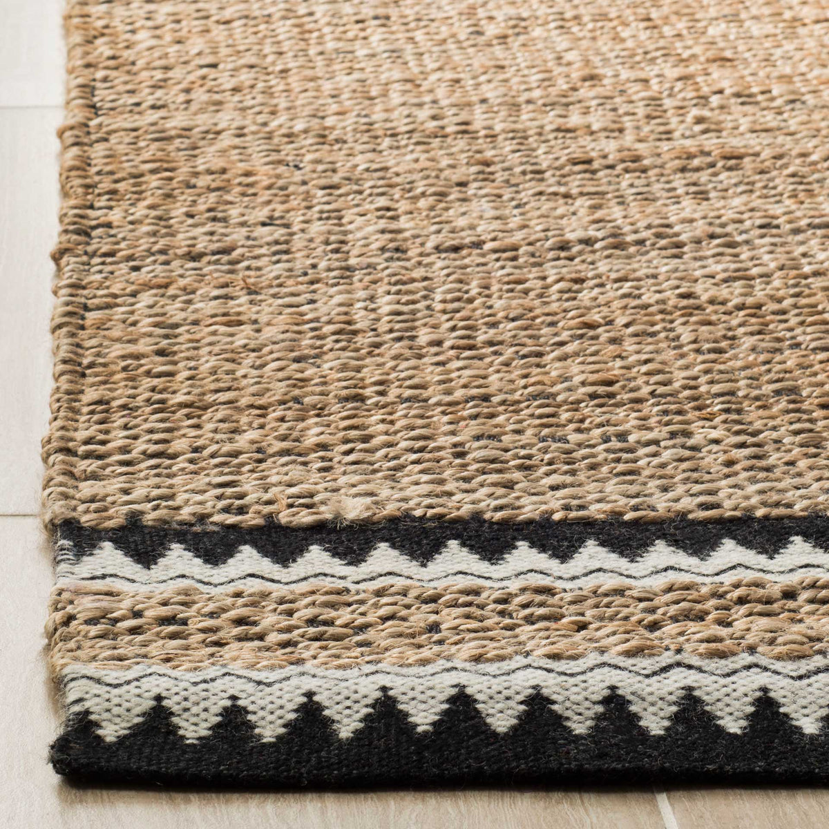 Black and ivory zigzag stripes finish the edge of a richly textured jute rug.