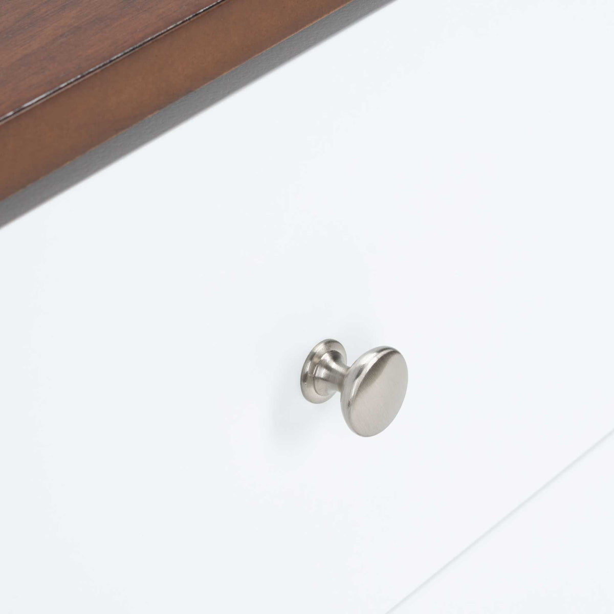 A round silver-tone knob lends a polished touch to the white drawer front.