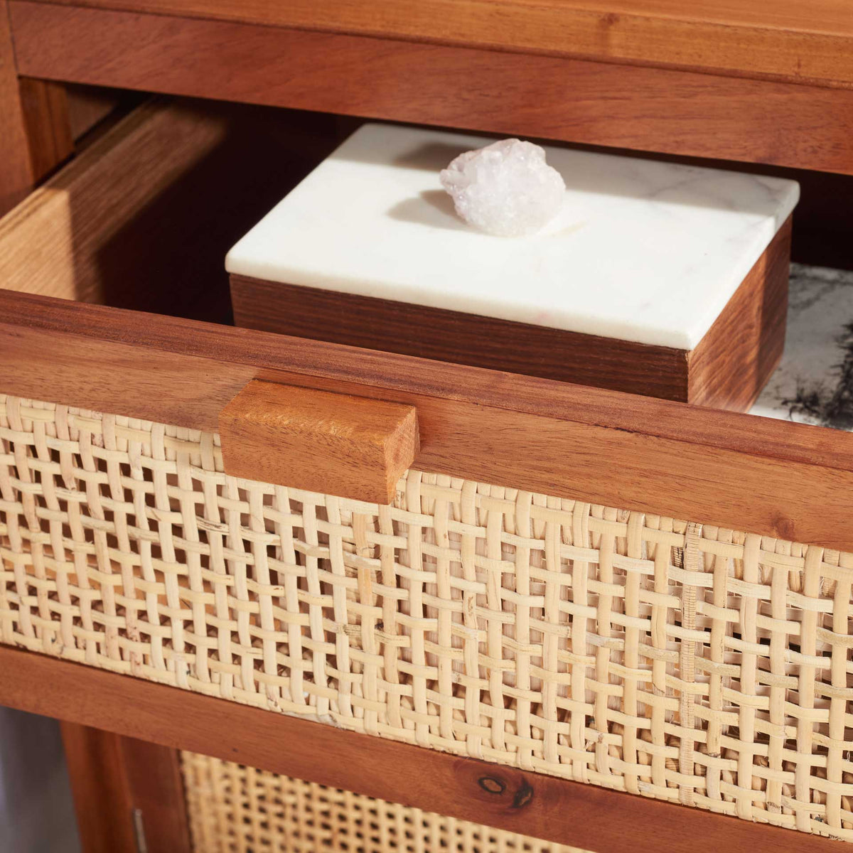 An open natural wood drawer tucks away small essentials behind its cane weave.