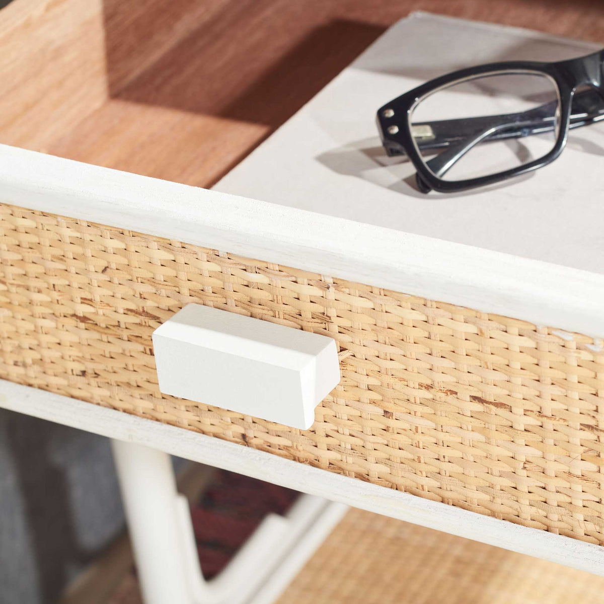 Open cane-front drawer holds everyday essentials behind a white block pull