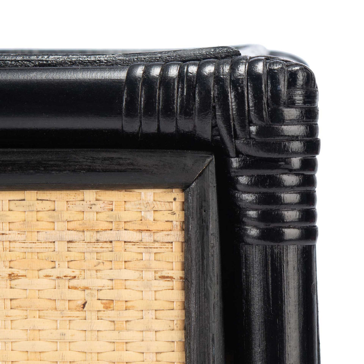 Wrapped black corner trim joins a smooth frame and tightly woven natural cane