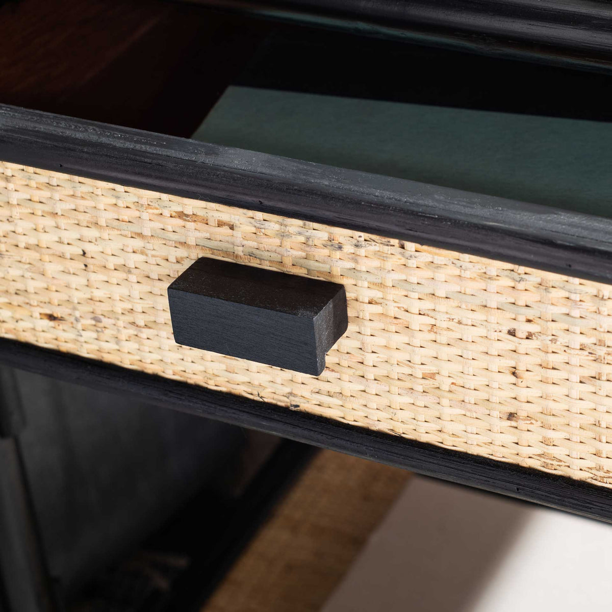 Open woven drawer and black block pull keep bedside storage within easy reach