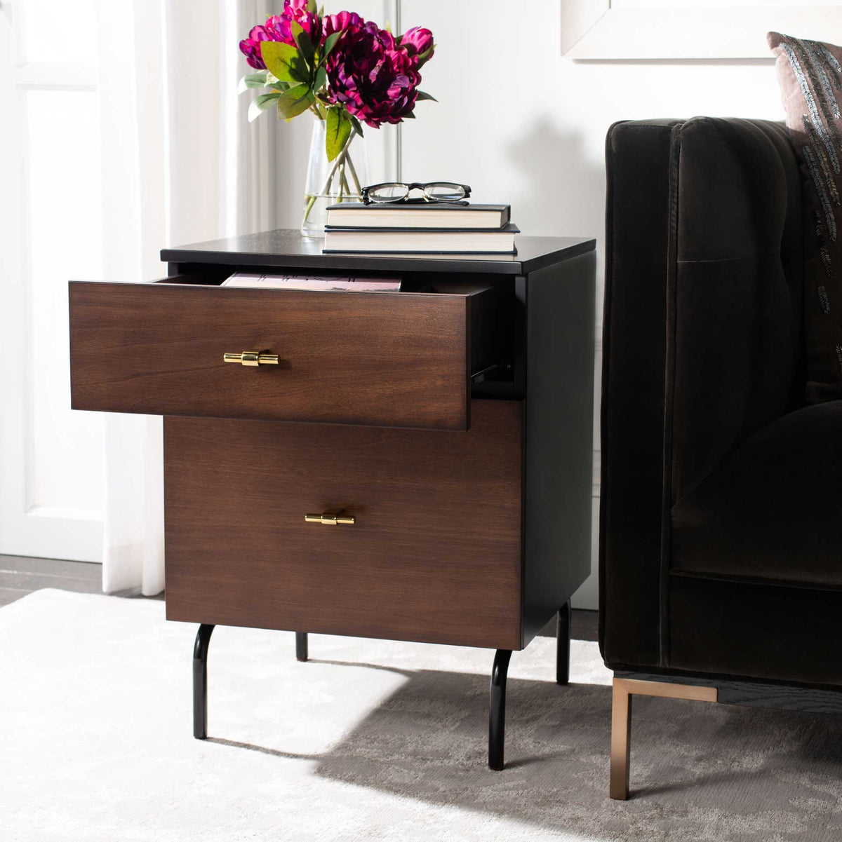 The top drawer opens for easy access to bedside items in a warm walnut and black cabinet.