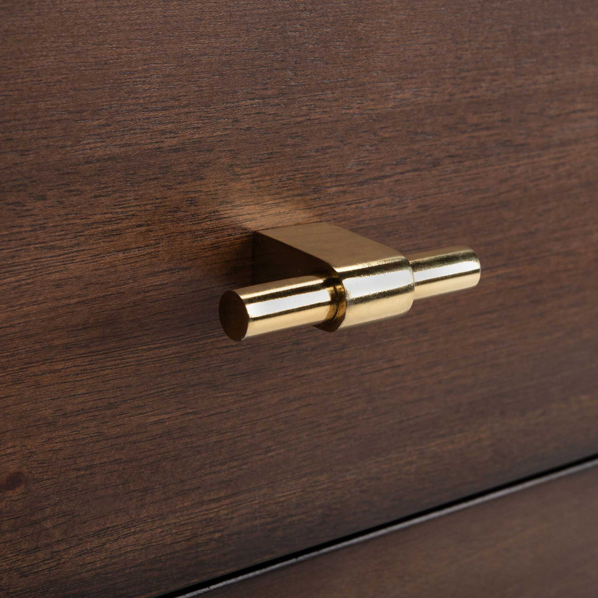 A polished gold-tone bar pull adds a bright accent to a richly grained walnut-finished drawer.