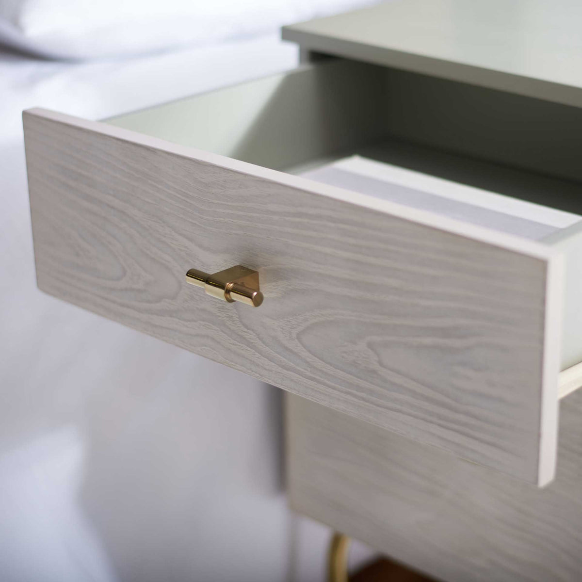 The upper drawer opens to a gray storage compartment above the wood-grain lower drawer.