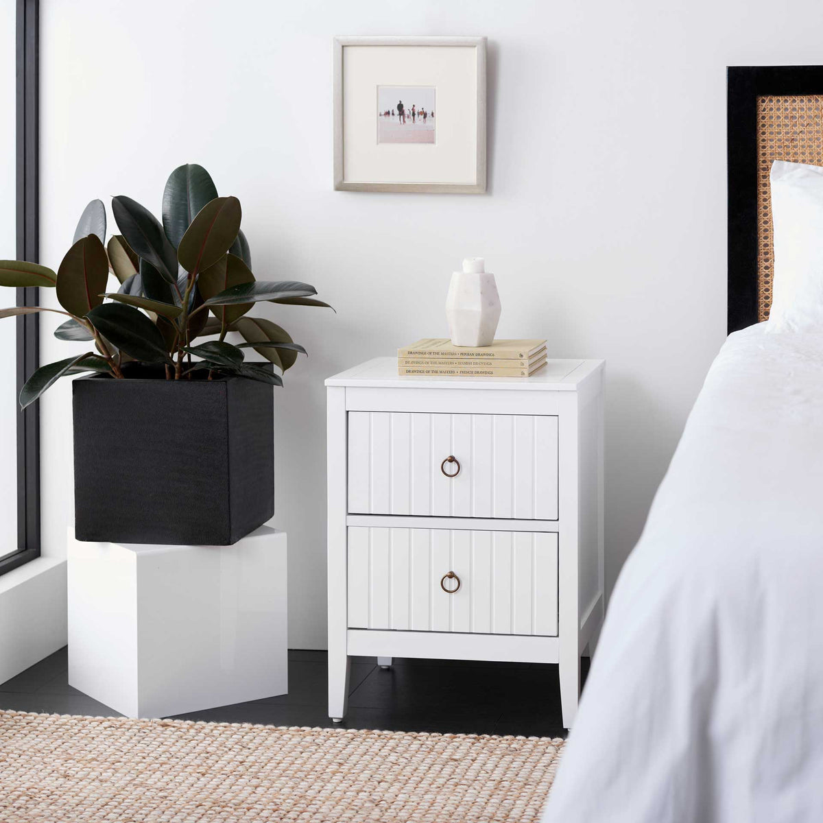 Vertical drawer detailing and brass ring pulls add texture to this bright bedside accent