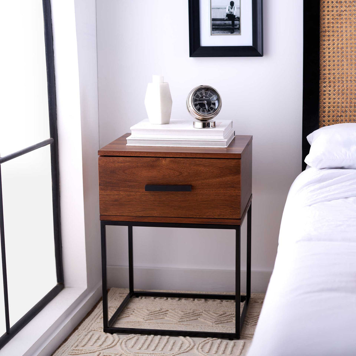 A wood-grain drawer and slim black frame add functional warmth beside the bed