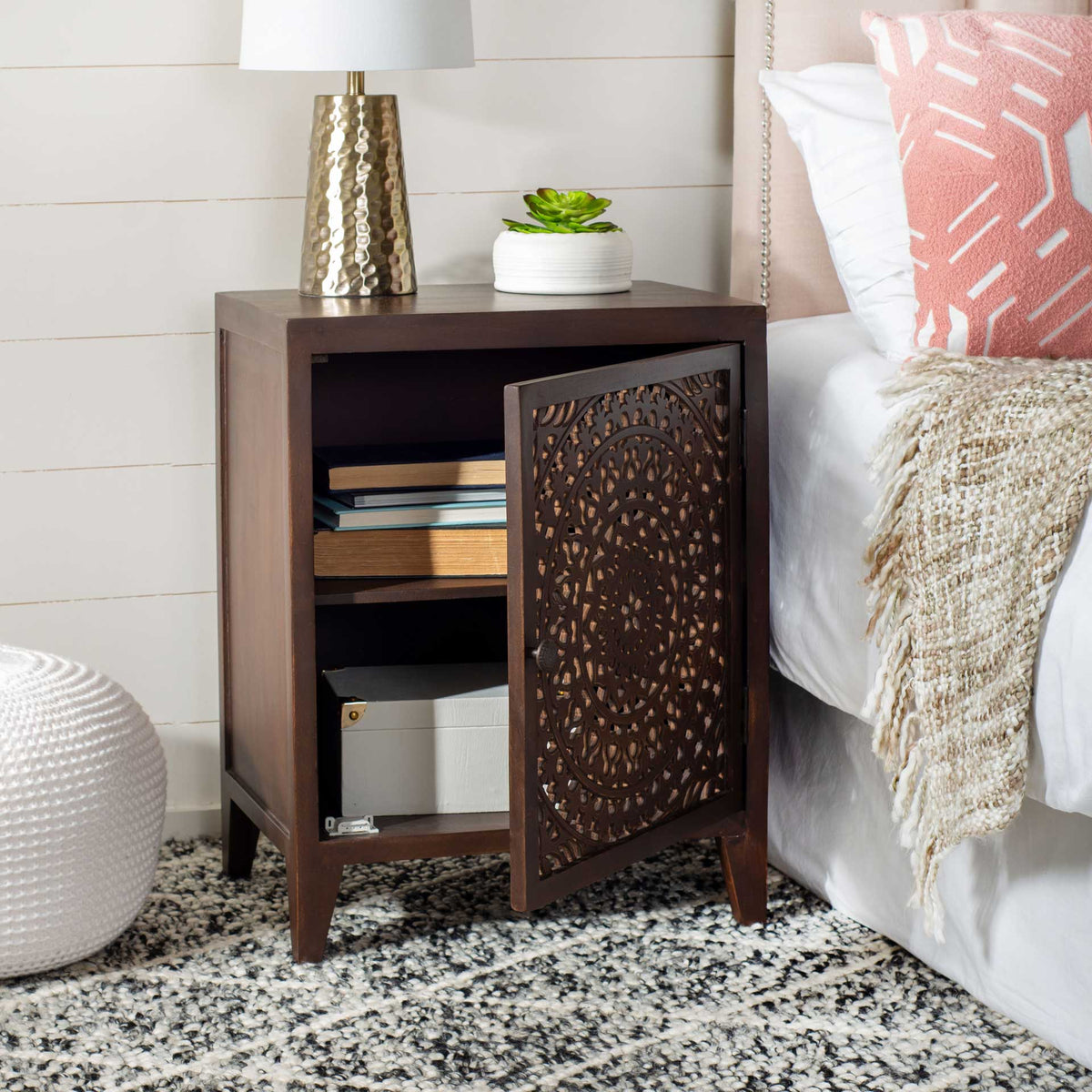 A carved brown door swings open to two storage compartments for bedside essentials