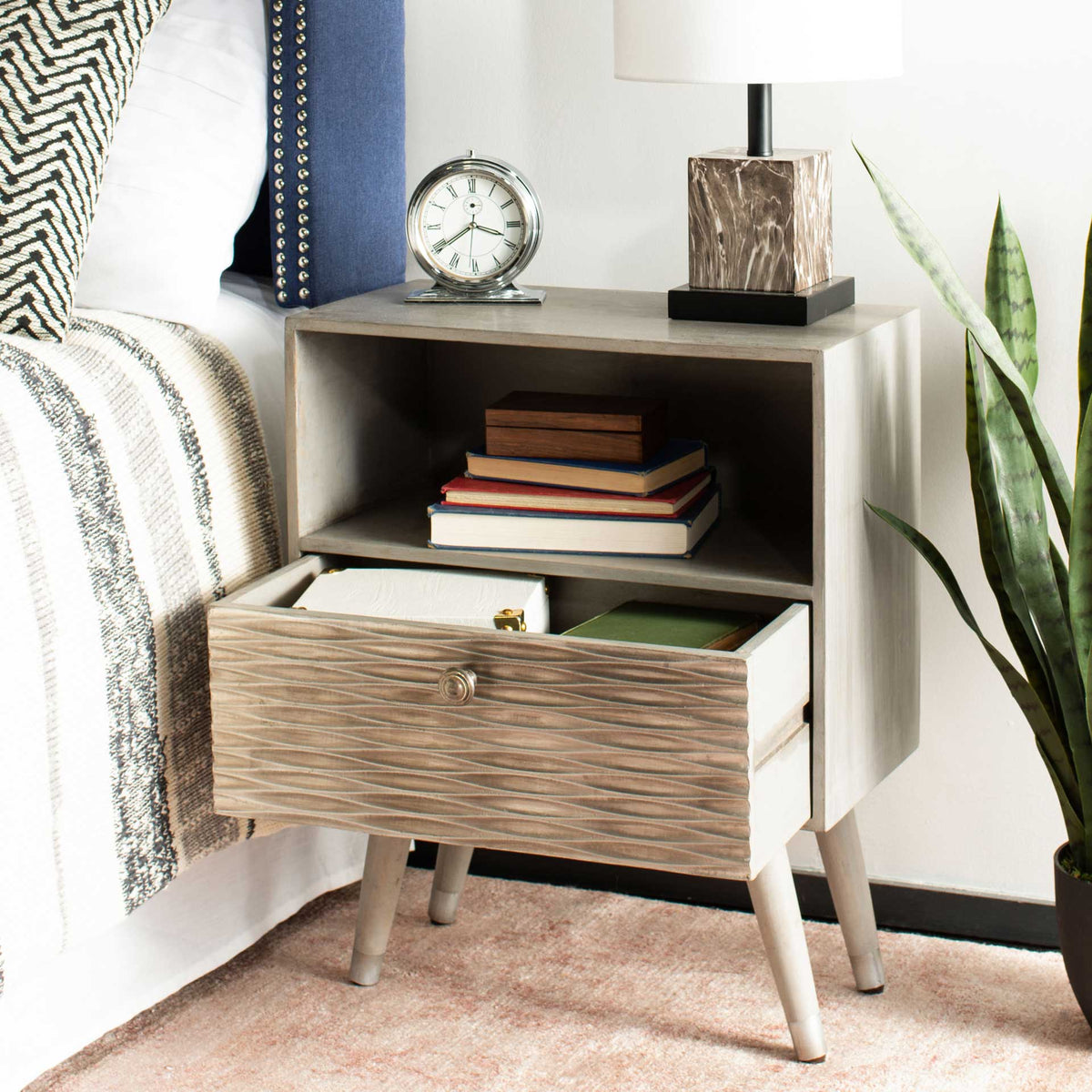 An open drawer reveals room for bedside essentials beneath the book-filled shelf
