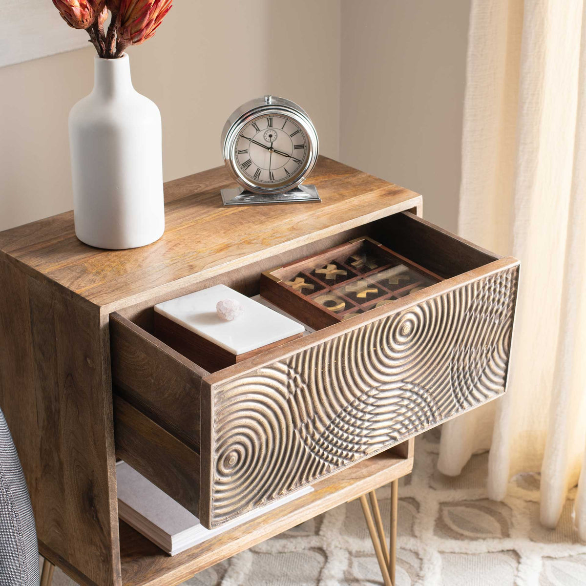 An extended wood drawer holds small essentials behind its textured metallic front, above an open shelf