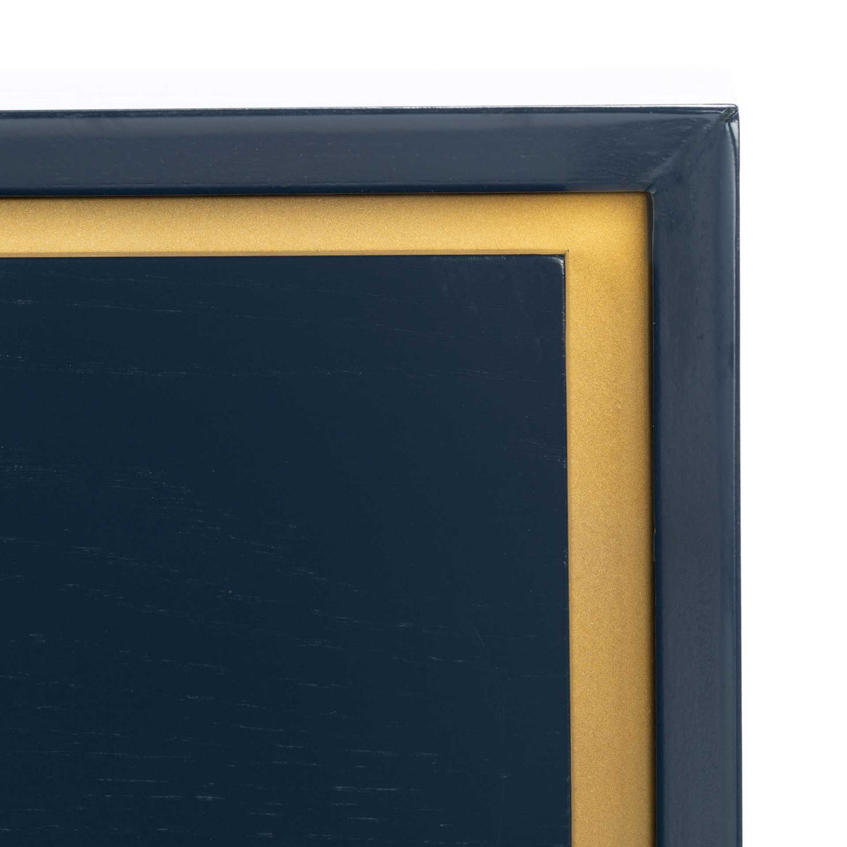 A warm brass-colored inset border frames the deep teal drawer face beneath a crisp cabinet edge