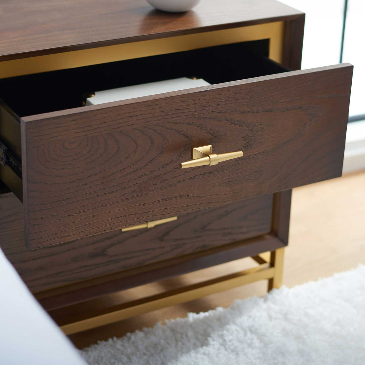 An open top drawer keeps bedside essentials within reach behind a warm walnut-finish front