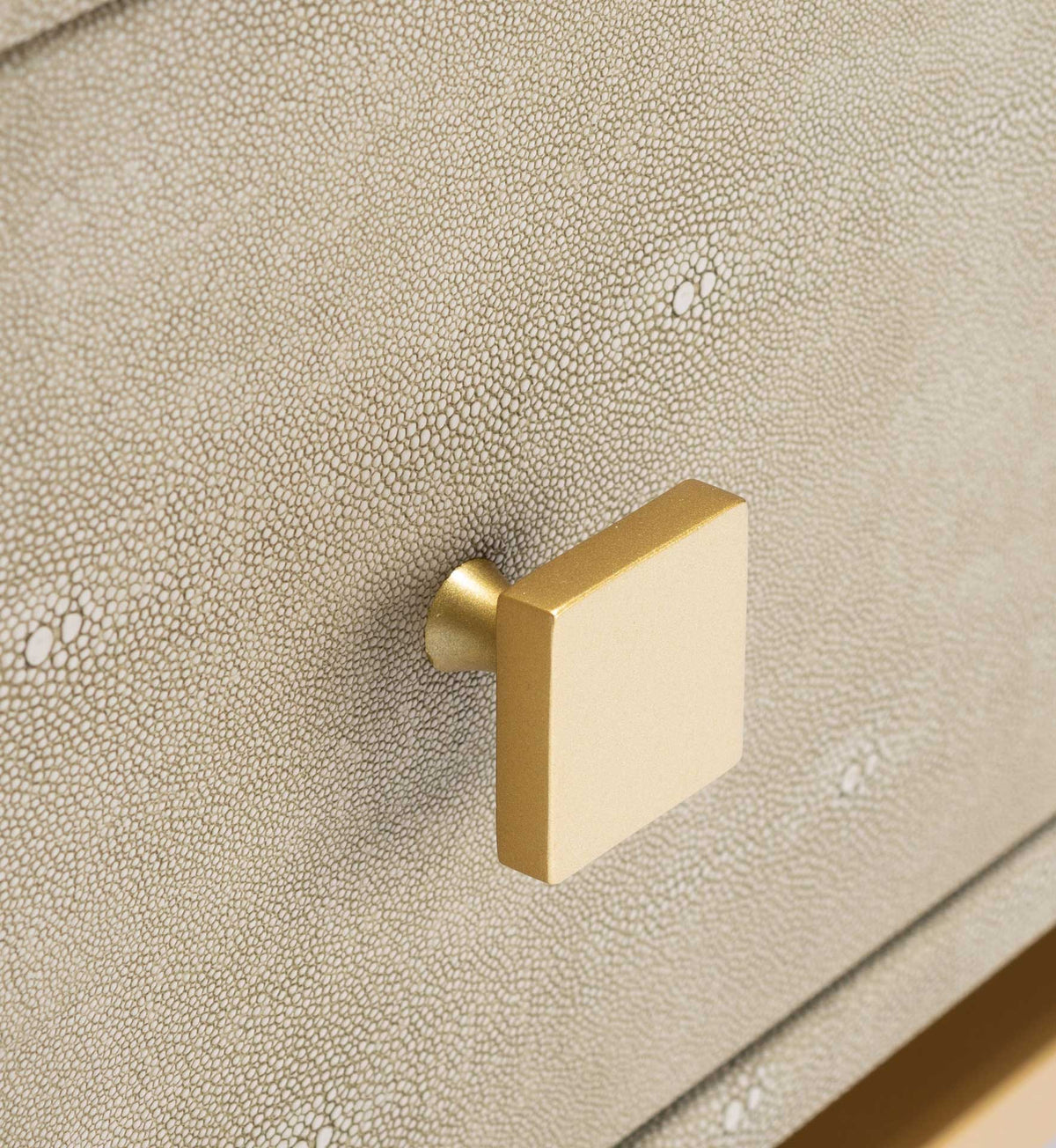 A square brass-tone pull adds warm metallic shine to the pebbled light taupe drawer front