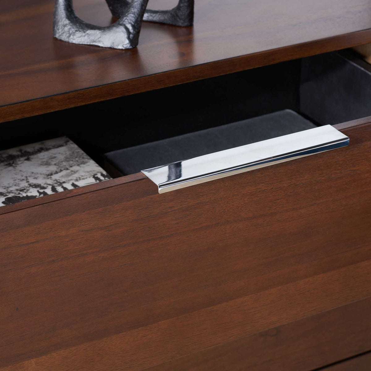 A polished chrome pull accents the open drawer and warm walnut grain