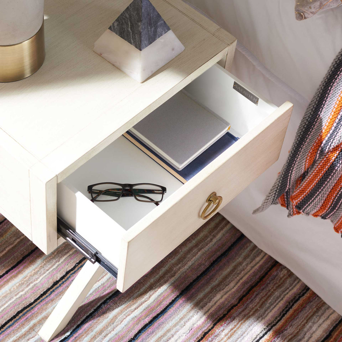 The open antique white drawer keeps books and glasses handy beside the bed.