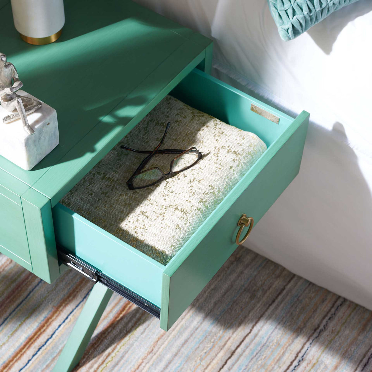The open turquoise drawer keeps glasses and folded linens close at hand.