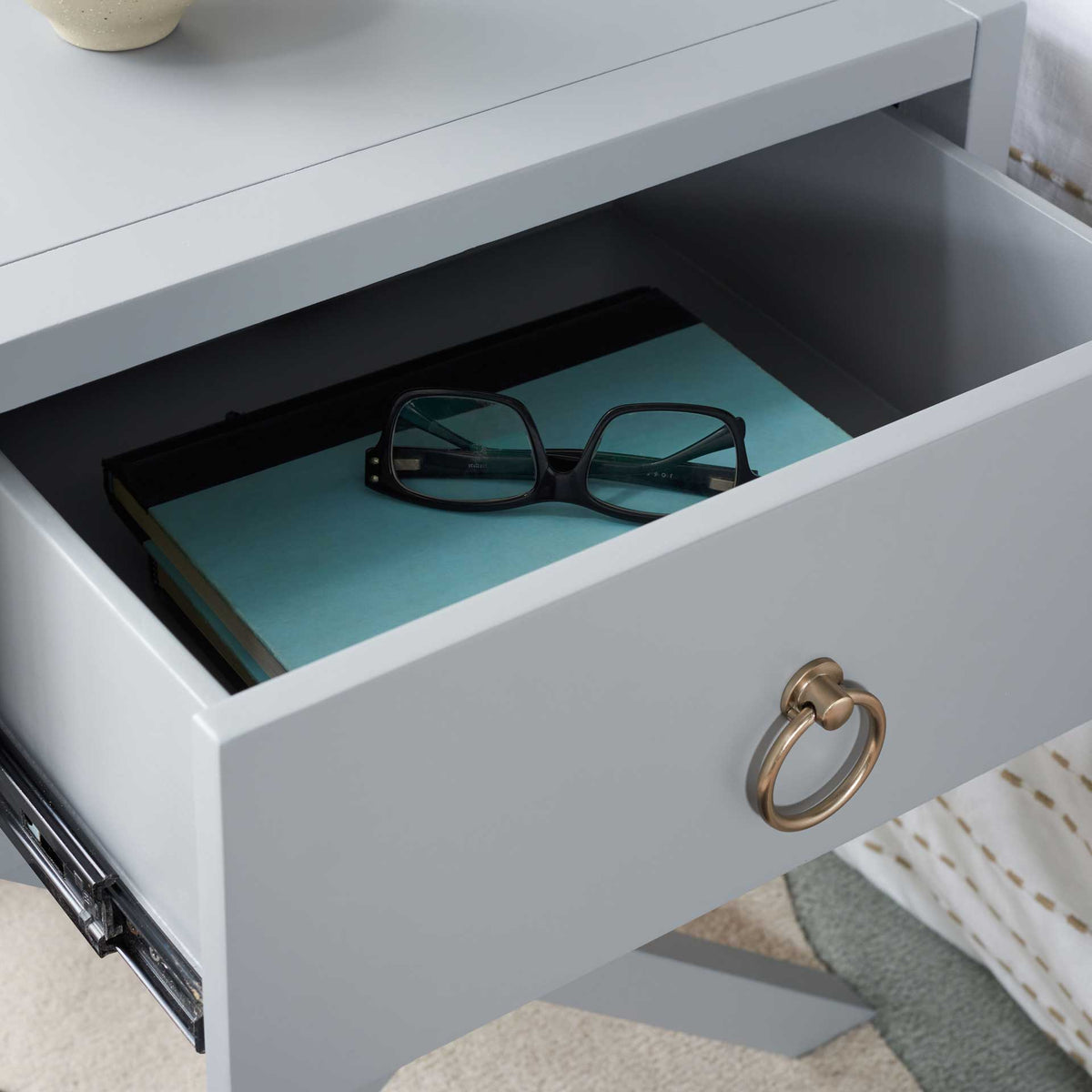 The open gray drawer offers easy access to books and glasses beside the bed.