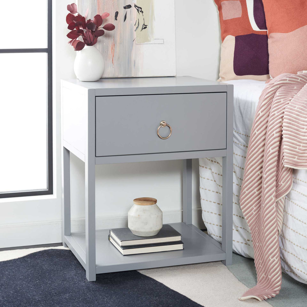 A gray bedside table keeps essentials within reach in its drawer and leaves room for books below.