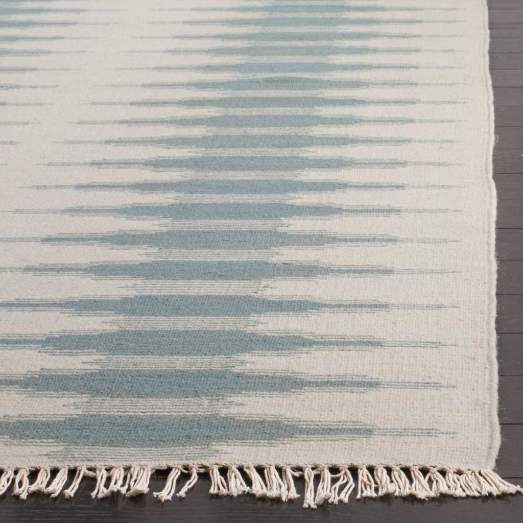 Ivory fringe accents the rug's woven edge and softly layered blue brushstrokes.