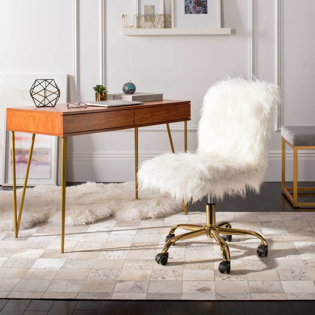 A fluffy white swivel chair with a polished gold-tone rolling base brightens a stylish home office.