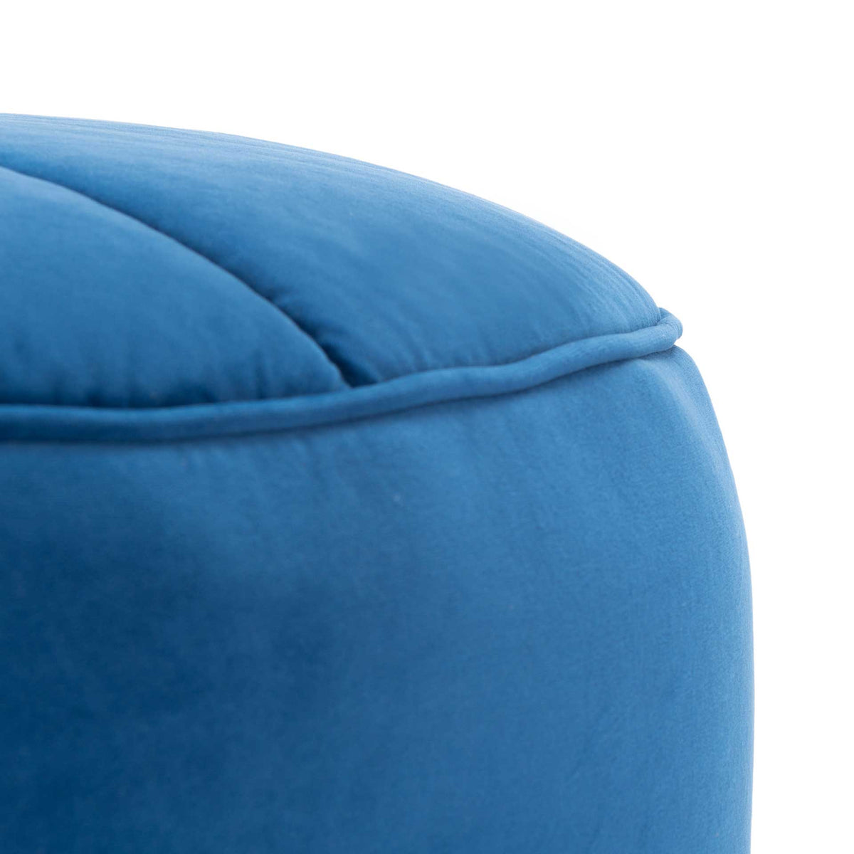 Plush navy velvet panels meet a neatly piped rim along the ottoman's curved edge.