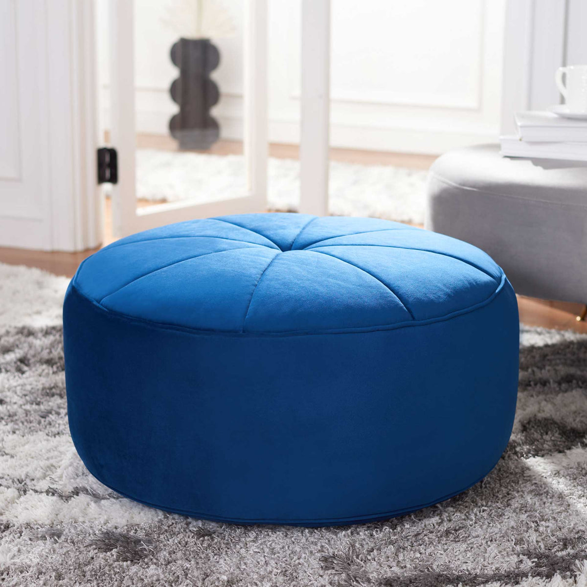 A plush navy ottoman brings a bold color accent and cushioned comfort to the living room.