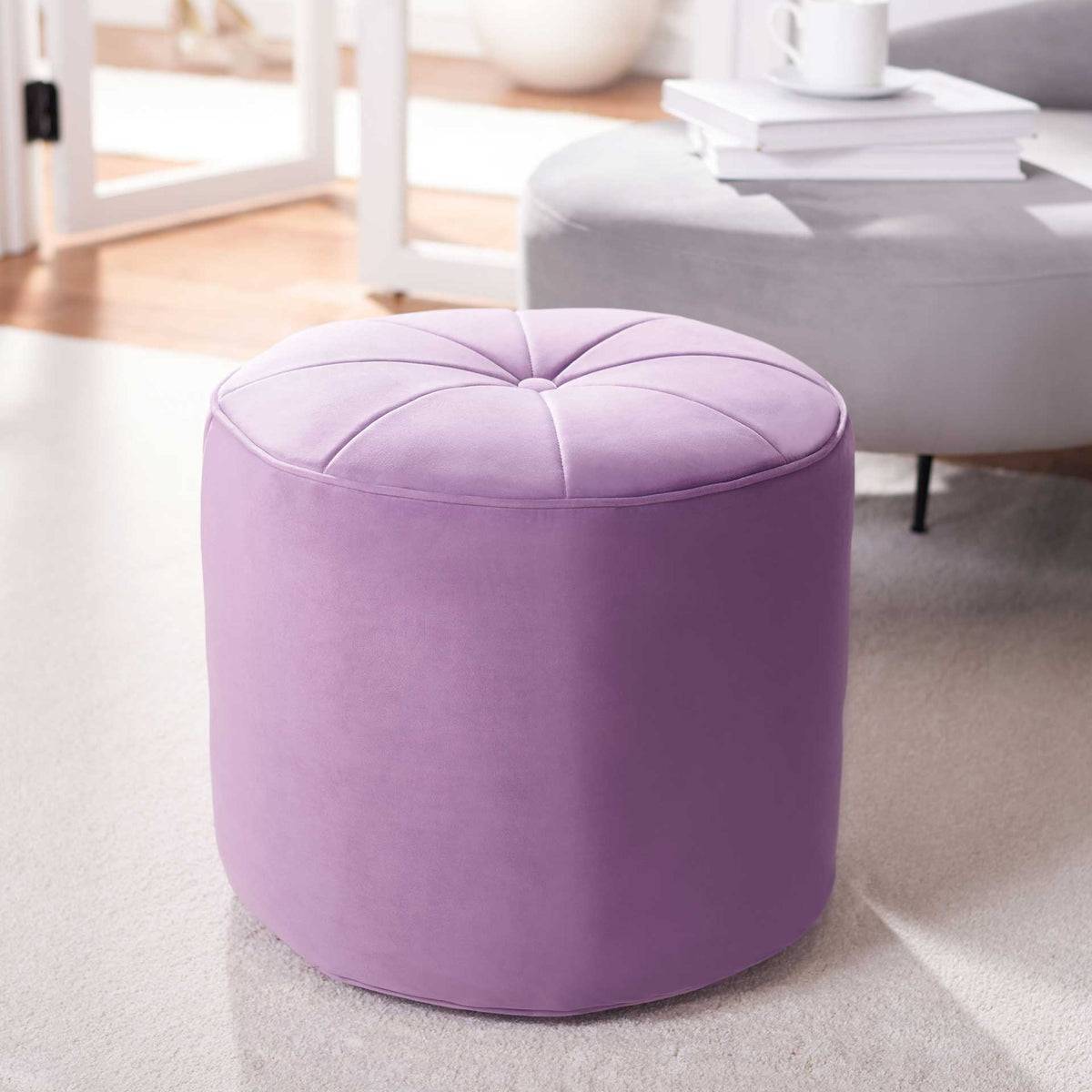 The lilac velvet ottoman brightens a living space with its cylindrical form and softly tufted seat.