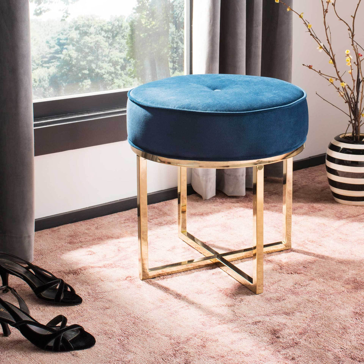 Rich navy velvet and gleaming brass-finish legs bring an elegant accent to the room