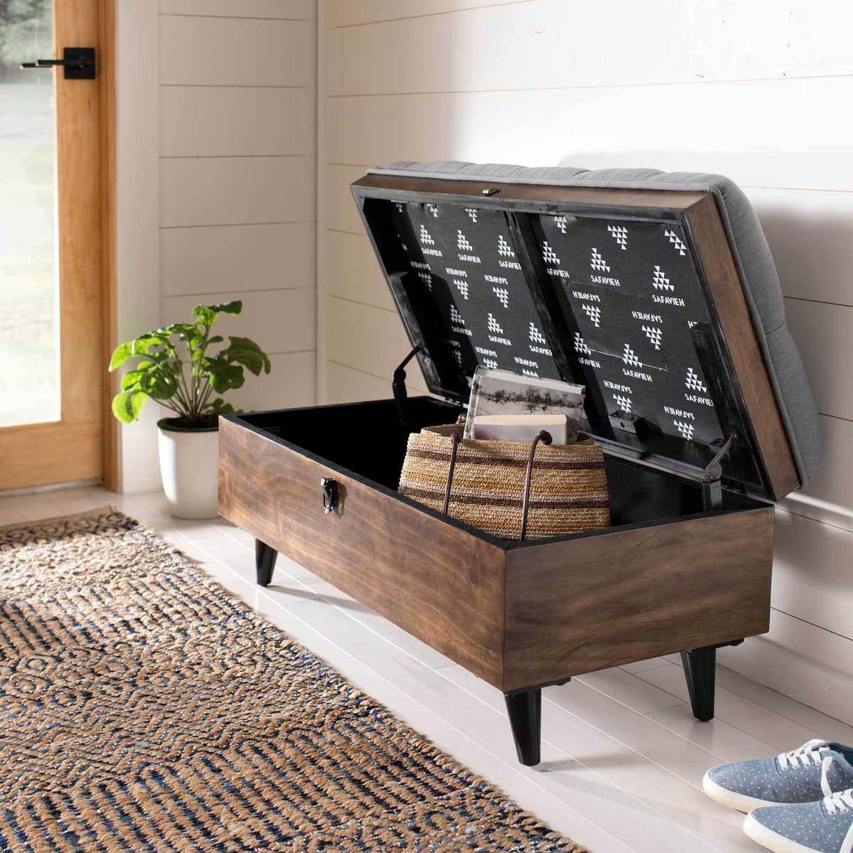 A gray upholstered lid lifts to reveal room for bags and other everyday essentials.