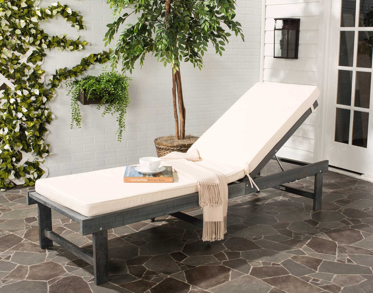 A beige cushioned chaise in ash gray wood makes an inviting place to unwind on the patio.