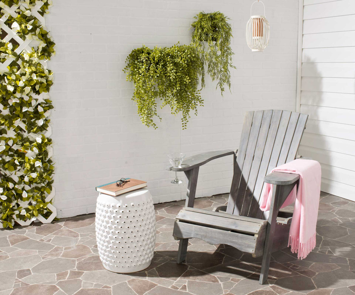 Ash gray Adirondack chair with a slatted back and wine glass holder sits on a stone patio