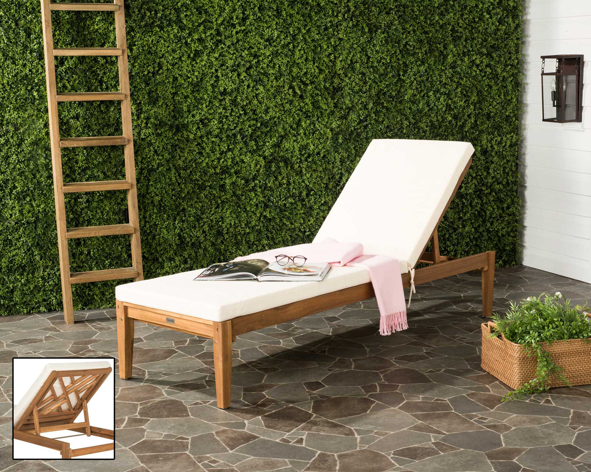 A natural acacia chaise and soft beige cushions create a laid-back retreat on a stone patio.