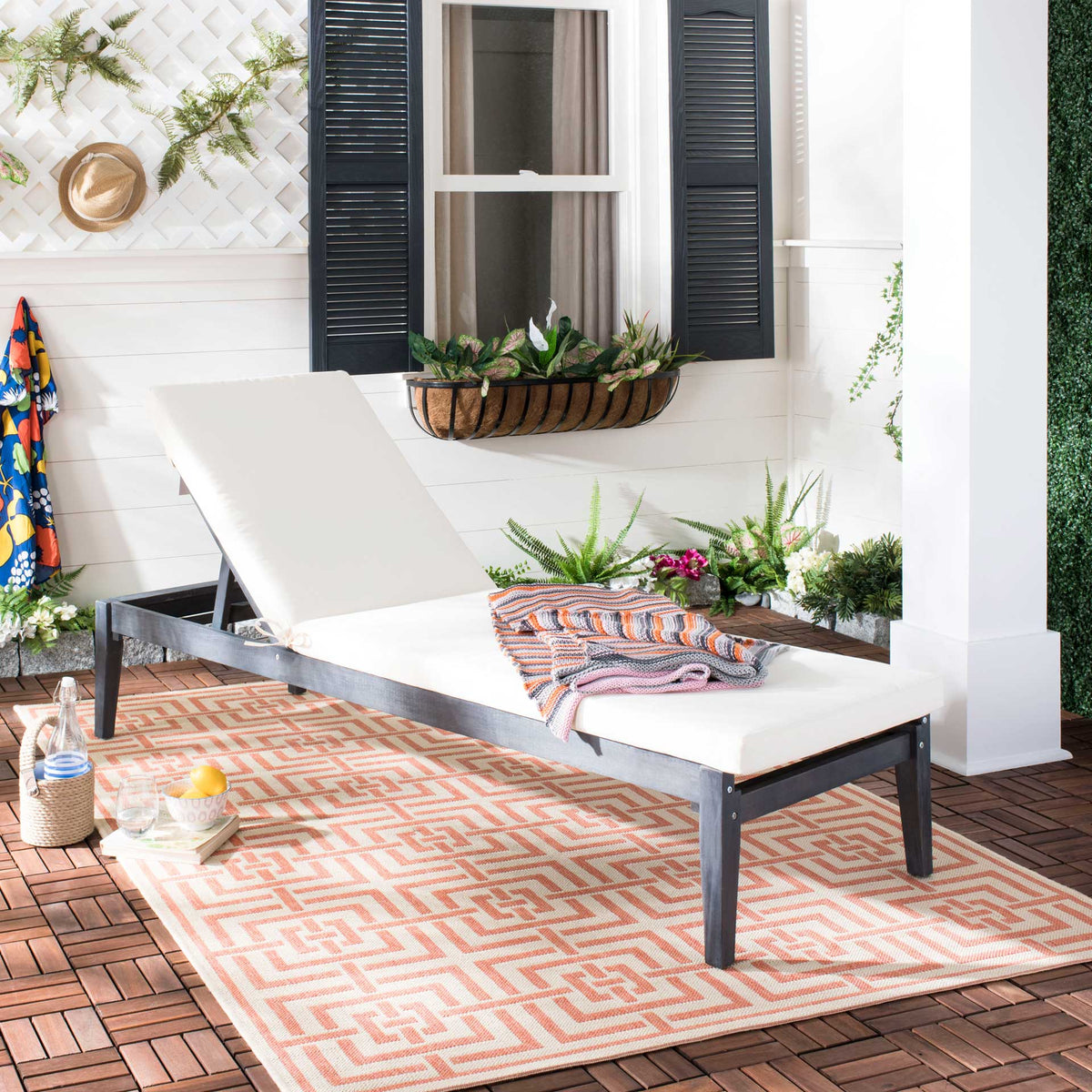 A dark slate gray chaise lounge softens the patio with its padded beige seat.