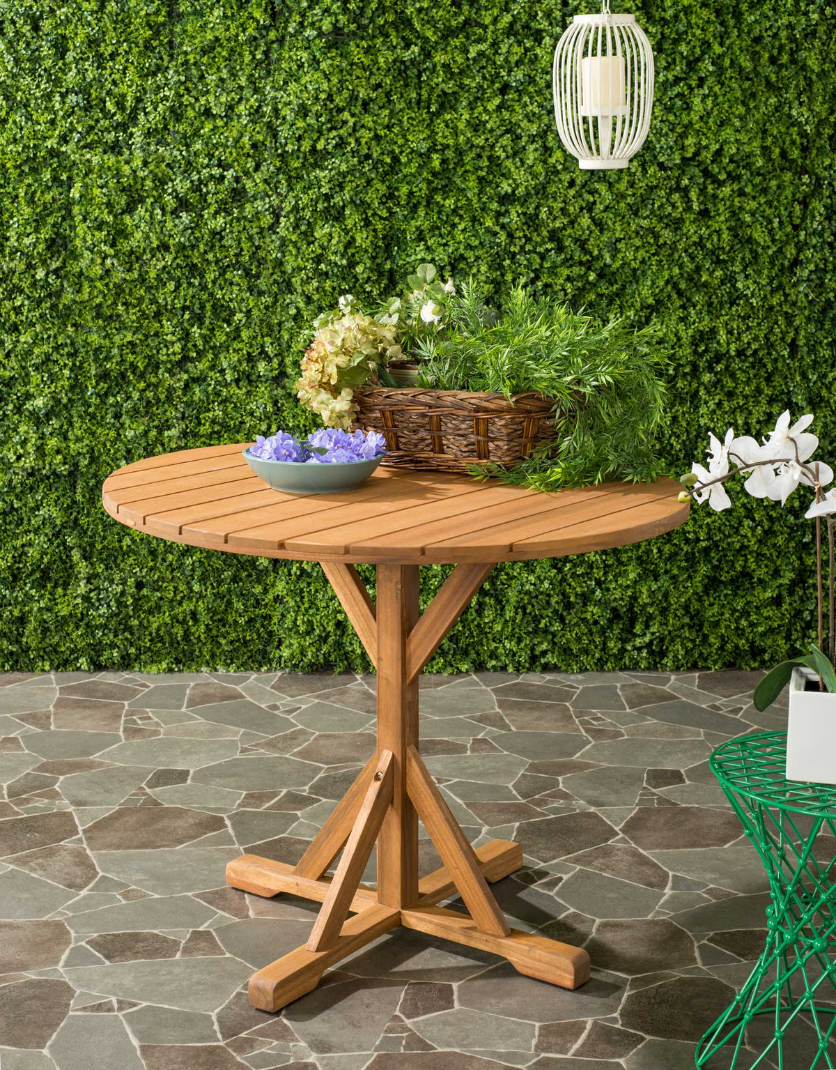 A natural acacia table adds a warm slatted surface and sturdy pedestal to a garden patio