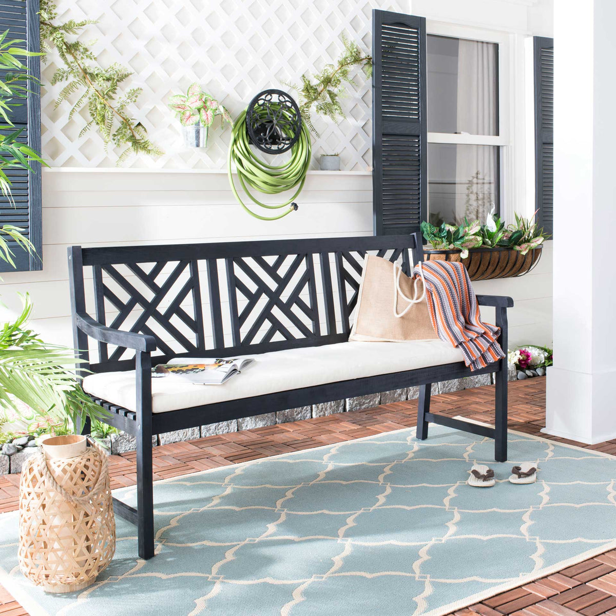 Dark slate gray lattice-back bench with a beige cushion creates a cozy spot on the patio
